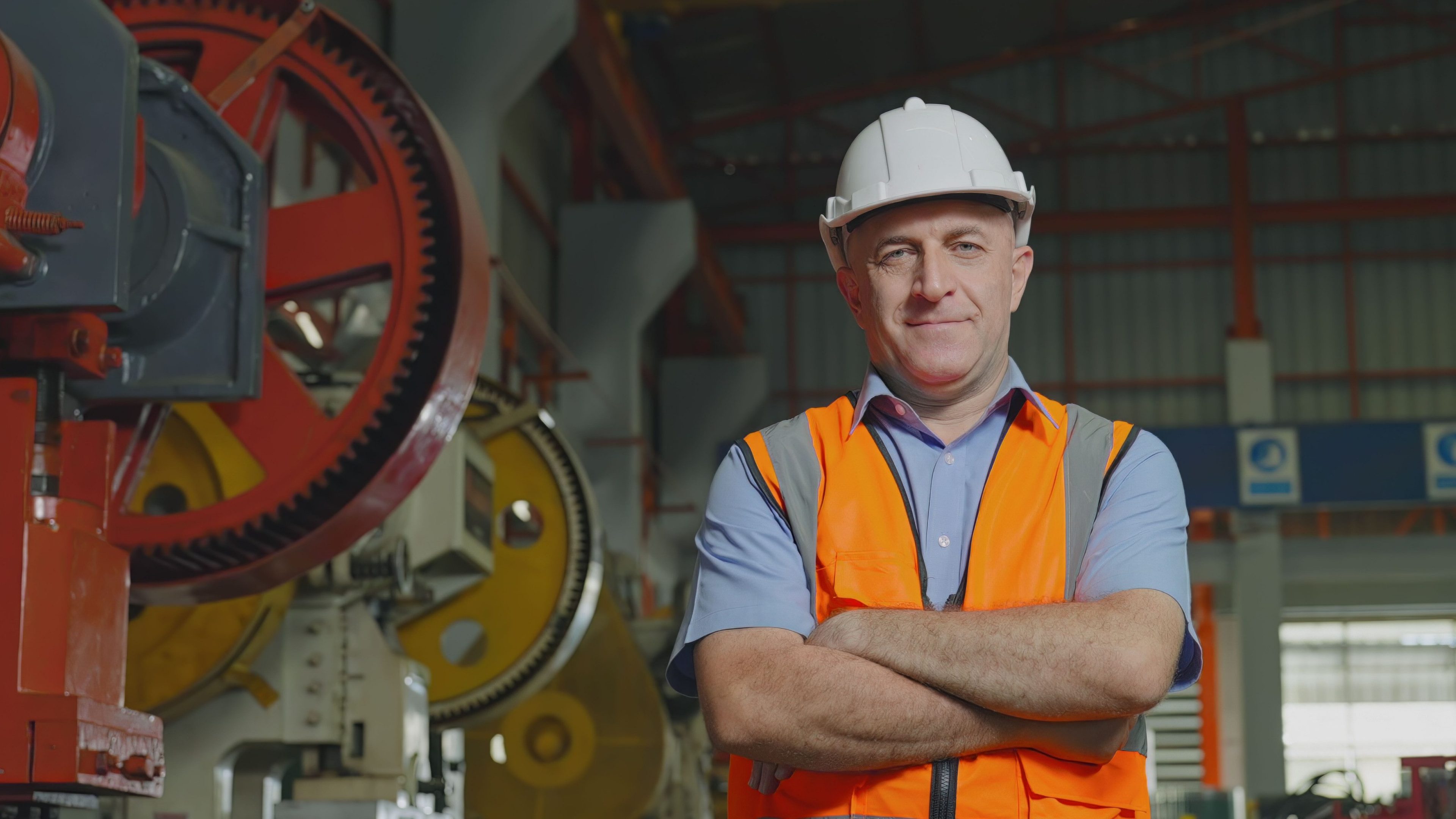Engineer standing wearing safety a hard hat and looking at the camera, Arms crossed and smiling in a factory industry. Senior man 48 years old